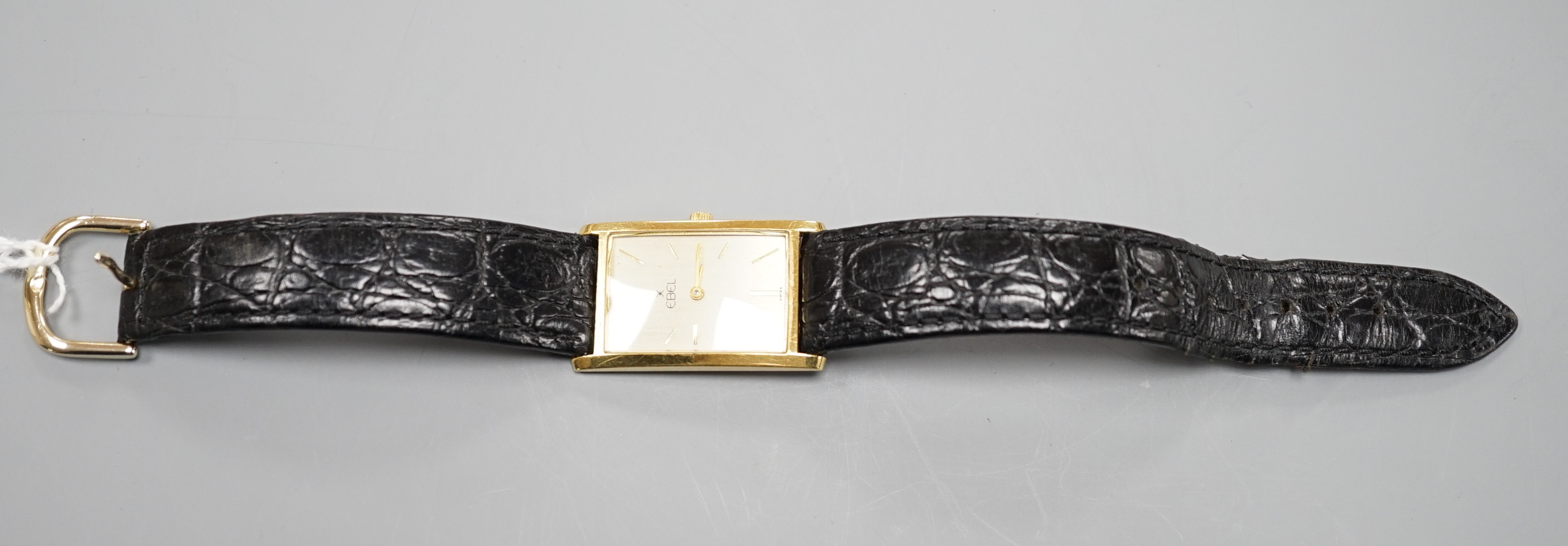 A gentleman's 750 yellow metal Ebel rectangular dial manual wind wrist watch, on associated leather strap, case diameter 22mm, gross weight 24.3 grams.